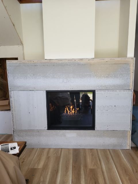 Fireplace insert burning mid-installation with unfinished drywall surround